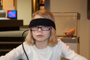 Mykala with a head band from a device that detects electrical signals in the forehead
